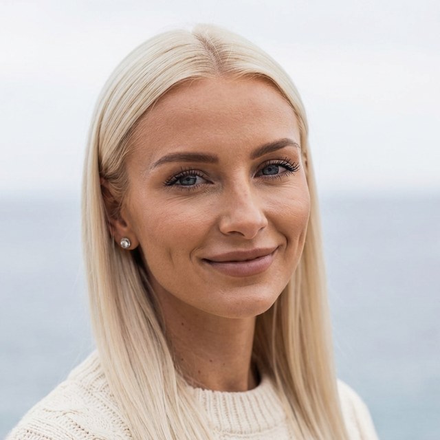 Lisa on a balcony by the sea in a cream sweater
